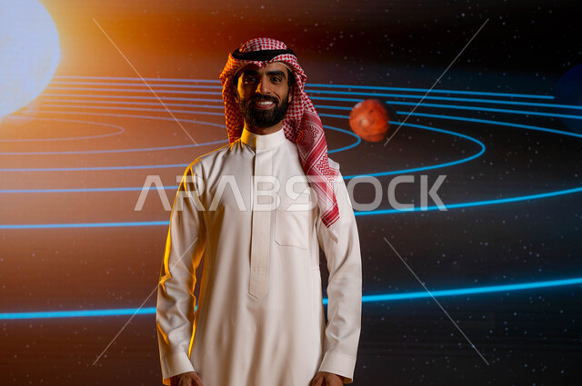 خلفية شاشة عرض لمسار حركة الارض والكواكب حول الشمس، نمو وتطوير قطاع الفضاء في السعودية، رجل اعمال سعودي عربي خليجي يقف امام شاشة الكترونية حديثة، ايماءات وجه تدل على السعادة، رحلة السعودية نحو الفضاء الخارجي، رؤية مستقبلية 2030