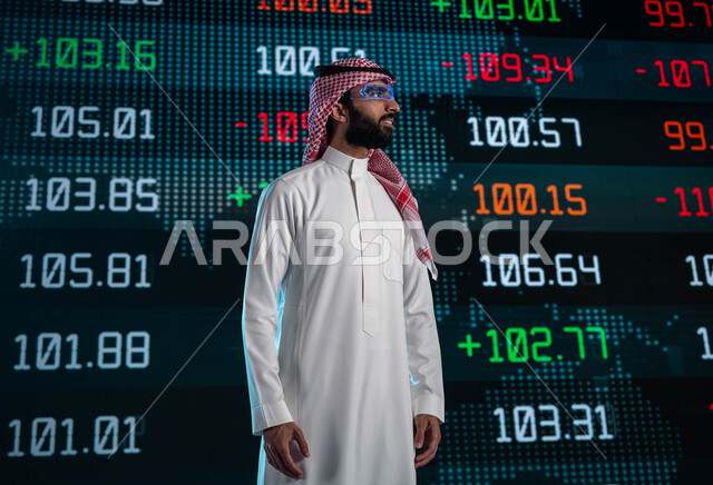 الإستثمار المالي والإقتصادي في البورصة السعودية، رجل اعمال عربي خليجي سعودي يرتدي نظارات الواقع الافتراضي، متابعة الأسهم المتداول بها في السعودية من خلال شاشات الكترونية حديثة، تحليل البيانات والمعلومات الرقمية، خلفية شاشة عرض رقمية للأسواق المالية
