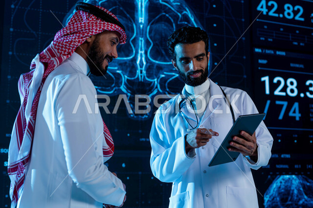 Magnetic resonance imaging in modern, advanced centers and hospitals. A Saudi Arab Gulf doctor wears a white coat and explains medical conditions to a man wearing a Saudi uniform through a tablet. The background of three-dimensional hologram screens of th