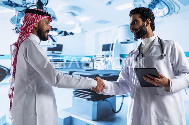 تعاقدات واتفاقيات عمل طبية سعودية ناجحة، طبيب عربي سعودي خليجي يرتدي المعطف الأبيض ويحمل بيده جهاز التابلت ويقوم بمصافحة رجل يرتدي الزي السعودي، معدات وأجهزة طبية إلكترونية متطورة في المستشفيات والمراكز والمستوصفات الحديثة، رؤية مستقبلية 2030