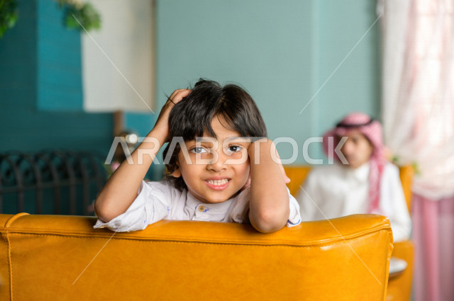 طفل عربي خليجي سعودي يقضي وقته مع والده في المطعم بايماءات و تعابير وجه تدل على السعادة ، قضاء العطلة مع العائلة ، أجواء عائلية ترفيهية ، جلسات فريدة و مميزة ، مطاعم و كافيهات في السعودية