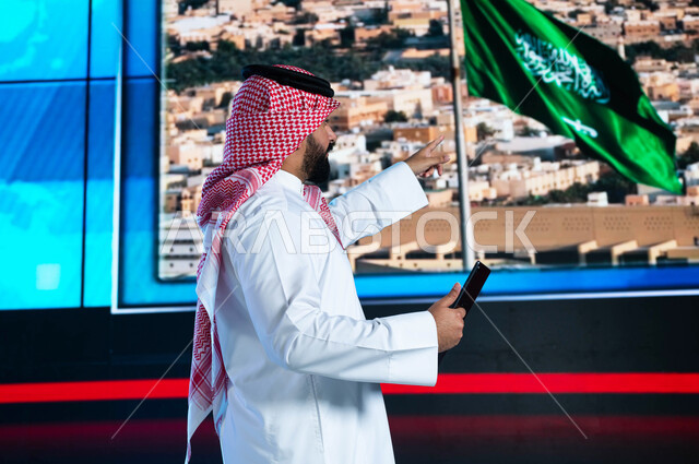 قراءة الموجز الإخباري بإستخدام التابليت، مذيع عربي سعودي خليجي يقوم بتقديم النشرة الإخبارية، الإحتفال بيوم العلم السعودي وإحياء ذكرى اليوم الوطني، دمج البيئة العملية مع التقنية والتكنولوجيا، خلفية شاشة إلكترونية لمدن ومعالم السعودية