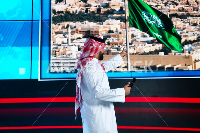 دمج البيئة العملية مع التقنية والتكنولوجيا، قراءة الموجز الإخباري بإستخدام التابليت، الإحتفال بيوم العلم السعودي وإحياء ذكرى اليوم الوطني، مذيع عربي سعودي خليجي يقوم بتقديم النشرة الإخبارية، خلفية شاشة إلكترونية لمدن ومعالم السعودية