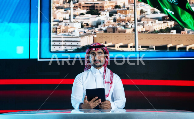 الإحتفال بيوم العلم السعودي وإحياء ذكرى اليوم الوطني، قراءة الموجز الإخباري بإستخدام التابليت، مذيع عربي سعودي خليجي يقوم بتقديم النشرة الإخبارية، دمج البيئة العملية مع التقنية والتكنولوجيا، خلفية شاشة إلكترونية لمدن ومعالم السعودية