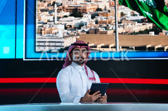 مذيع عربي سعودي خليجي يقوم بتقديم النشرة الإخبارية، قراءة الموجز الإخباري بإستخدام التابليت، دمج البيئة العملية مع التقنية والتكنولوجيا، خلفية شاشة إلكترونية لمدن ومعالم السعودية، الإحتفال بيوم العلم السعودي وإحياء ذكرى اليوم الوطني
