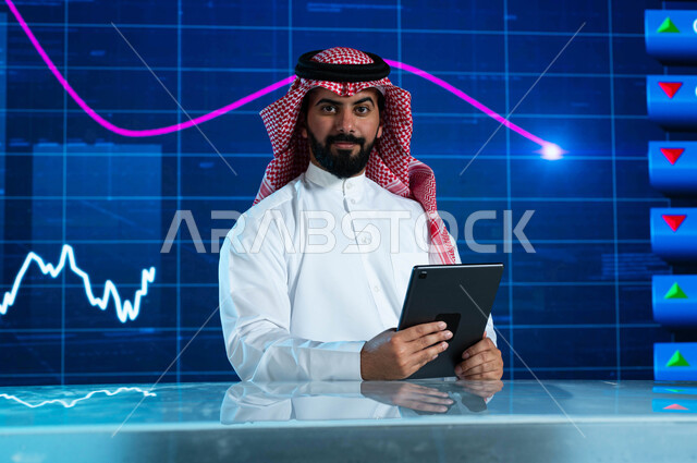 دمج البيئة العملية مع التقنية والتكنولوجيا، مذيع وإعلامي عربي خليجي سعودي يقوم بقراءة الموجز الأخباري من خلال جهاز التابلت، تقديم الأخبار الإقتصادية السعودية، التغيرات الحاصلة في أسعار السلع والثروات، خلفية شاشة إلكترونية حديثة لصعود وهبوط مؤشر الأسهم