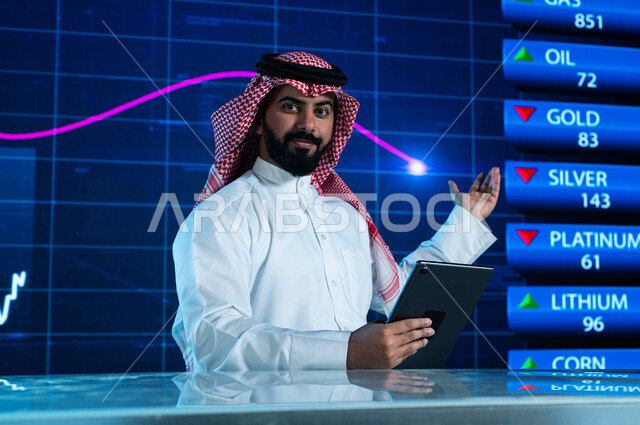 تقديم الأخبار الإقتصادية السعودية، مذيع وإعلامي عربي خليجي سعودي يقوم بقراءة الموجز الأخباري من خلال جهاز التابلت، التغيرات الحاصلة في أسعار السلع والثروات، دمج البيئة العملية مع التقنية والتكنولوجيا، خلفية شاشة إلكترونية حديثة لصعود وهبوط مؤشر الأسهم