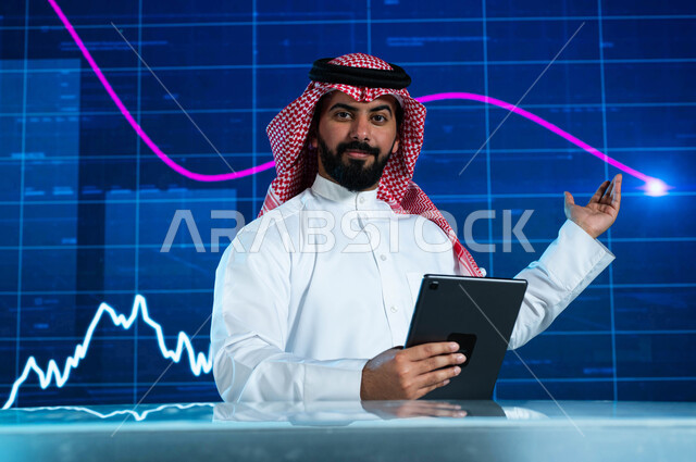 مذيع وإعلامي عربي خليجي سعودي يقوم بتقديم النشرات الإخبارية الإقتصادية، التغيرات الحاصلة في أسعار السلع والثروات، قراءة الموجز الأخباري بإستخدام جهاز التابلت، خلفية شاشة إلكترونية حديثة لصعود وهبوط مؤشر الأسهم والبورصة