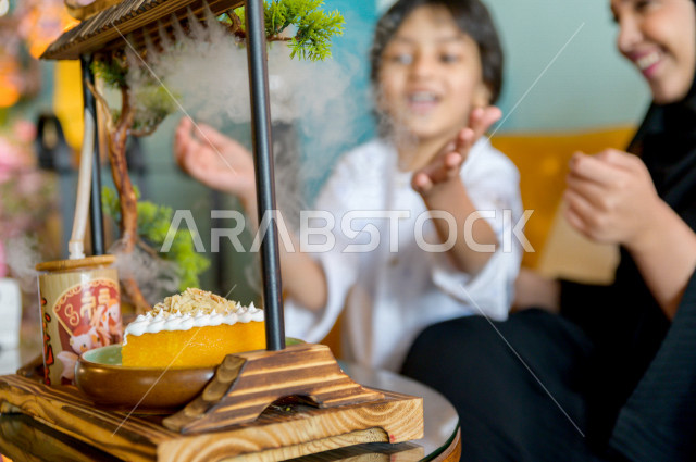 طفل عربي خليجي سعودي يقضي وقته مع والدته في المطعم بايماءات و تعابير وجه تدل على السعادة ، الاحتفال بعيد ميلاد ، قضاء العطلة مع العائلة ، أجواء عائلية ترفيهية ، جلسات فريدة و مميزة ، مطاعم و كافيهات في السعودية