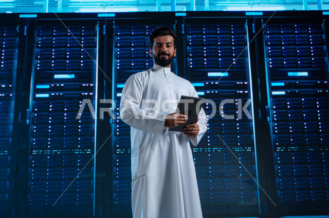 3D hologram background of the data center, a Saudi Arabian Gulf man uses a tablet and manages the servers control room and giant Internet servers, investing Saudi expertise in building advanced and modern data centers