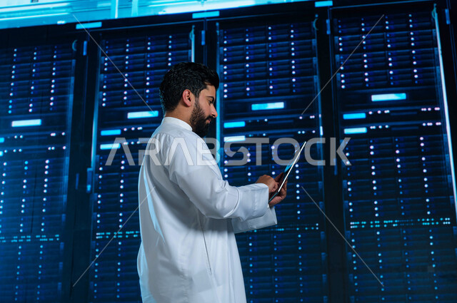 غرفة التحكم بالسيرفرات وخوادم الانترنت، رجل عربي خليجي سعودي يقوم بالتحكم بالمواقع المستضافة على السيرفرات من خلال جهاز التابلت، تسهيل الوصول للمعلومات من خلال نظم قواعد البيانات، خلفية هولوجرامية ثلاثية الأبعاد لمركز البيانات