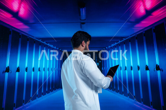 خلفية هولوجرامية ثلاثية الأبعاد لمركز البيانات، تسهيل الوصول للمعلومات من خلال نظم قواعد البيانات، رجل عربي خليجي سعودي يقوم بالتحكم بالمواقع المستضافة على السيرفرات من خلال جهاز التابلت، غرفة التحكم بالسيرفرات وخوادم الانترنت