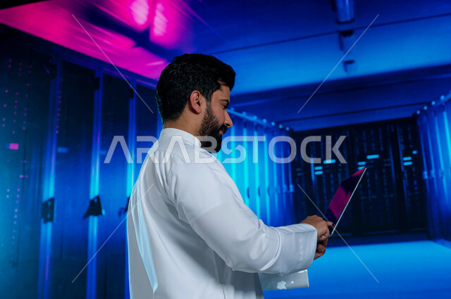 خلفية هولوجرامية ثلاثية الأبعاد لغرفة التحكم بالسيرفرات وخوادم الانترنت، إستثمار الخبرات السعودية في بناء مراكز بيانات متطورة وحديثة، رجل عربي خليجي سعودي يستخدم جهاز التابليت في الإشراف وإدارة معلومات الداتا سنتر، مفهوم  تكنولوجيا التخزين السحابي