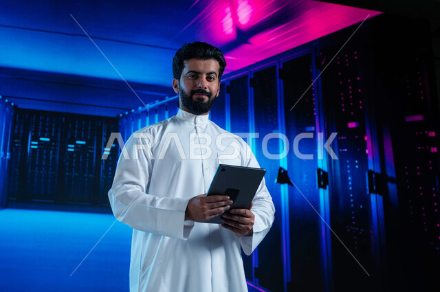 Servers and Internet servers control room, facilitating access to information through database systems, a Saudi Arabian Gulf man controlling websites hosted on servers through a tablet, a 3D hologram background for the data center