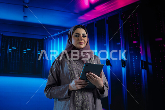 الاستفادة من الخبرات السعودية في تطوير الداتا سنتر، امرأة عربية خليجية سعودية تقوم بالإشراف والتحكم في مركز البيانات باستخدام جهاز التابليت، تسهيل الوصول للمعلومات من خلال نظم قواعد البيانات، خلفية هولوجرامية ثلاثية الأبعاد لغرفة الخوادم والسيرفرات