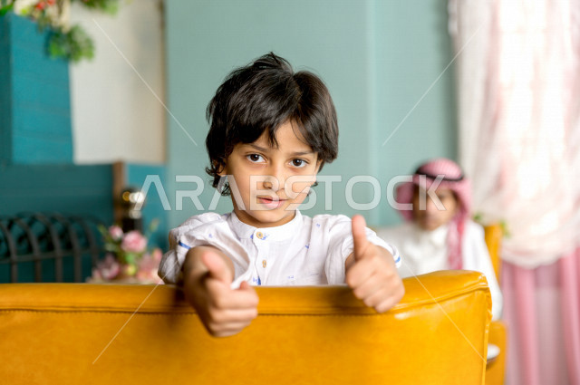 طفل عربي خليجي سعودي يقضي وقته مع والده في المطعم بايماءات و تعابير وجه تدل على السعادة ، قضاء العطلة مع العائلة ، أجواء عائلية ترفيهية ، جلسات فريدة و مميزة ، مطاعم و كافيهات في السعودية