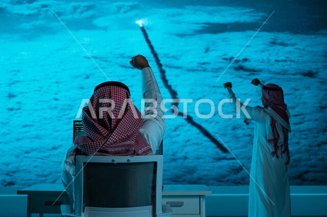 صورة من الخلف لفريق عمل يقوم بمراقبة لحظة انطلاق المكوك الفضائي من السعوديه ،  ايماءات التشجيع لنجاح انطلاق السفينة الفضائيه, مركز مراقبة رحلات الفضاء, رحلة عربيه سعوديه الى الفضاء الخارجي ،خلفية شاشات حديثه ، رؤية 2030