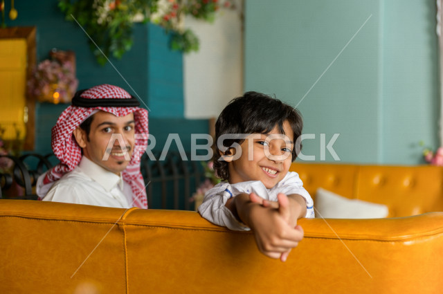 طفل عربي خليجي سعودي يقضي وقته مع والده في المطعم بايماءات و تعابير وجه تدل على السعادة ، قضاء العطلة مع العائلة ، أجواء عائلية ترفيهية ، جلسات فريدة و مميزة ، مطاعم و كافيهات في السعودية