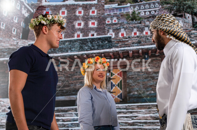 عادات وتقاليد شعبيه ،قرية رجال ألمع التراثية في منطقة عسير،الوقوف أمام الأثار التاريخية القديمة في أبها ،صورة مقربة لرجل عربي خليجي يرتدي الزي الجنوبي الشعبي مع الزائرين الاجانب يرتدون اكليل من الورد العسيري العطري ويتبادلون الأحاديث, معالم سياحية مشهورة