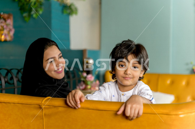 طفل عربي خليجي سعودي يقضي وقته مع والدته في المطعم بايماءات و تعابير وجه تدل على السعادة ، قضاء العطلة مع العائلة ، أجواء عائلية ترفيهية ، جلسات فريدة و مميزة ، مطاعم و كافيهات في السعودية