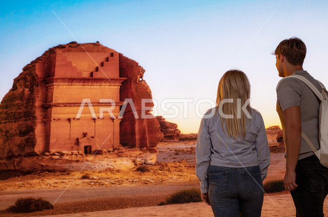 فتح ابواب السياحه السعودية، صورة من الخلف للسياح الأجانب أمام قصر الفريد في محافظة العلا في السعودية, الاستمتاع في الطبيعة الصحراوية في الأماكن السياحية في السعودية, انشطه و فعاليات ترفيهيه ممتعه، معالم أثرية تاريخية قديمة، قدوم الزوار من شتى أنحاء العالم