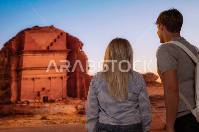 صورة من الخلف للسياح الأجانب أمام قصر الفريد في محافظة العلا في السعودية, الاستمتاع في الطبيعة الصحراوية في الأماكن السياحية في السعودية, انشطه و فعاليات ترفيهيه ممتعه، معالم أثرية تاريخية قديمة، فتح ابواب السياحه السعودية، قدوم الزوار من شتى أنحاء العالم