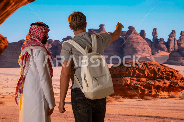 فعاليات ترفيهيه سياحية في السعودية، مرشد سياحي عربي، القمم و المرتفعات الجبلية الصخرية في محافظة العلا, معالم قديمة أثرية تاريخية ،موقع أثري في اليونسكو, صورة مقربة من الخلف لزائر اجنبي مع رجل سعودي يشير بيده الى شيء ما، فتح ابواب السياحه السعودية