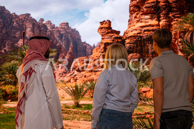 Opening the doors of Saudi tourism, a picture from the back of foreign visitors with a Saudi Arabian Gulf tour guide enjoying the distinct mountainous nature in the Al-Ula region in Saudi Arabia, the famous tourist historical monuments, an archaeological 