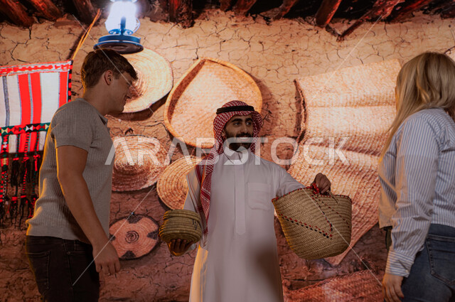 الادوات الشعبيه اليدويه المصنوعه من القش في متجر الهدايا والتذكارات ، الترحيب وحسن الاستقبال للزوار الأجانب, السياحه في الاسواق الشعبيه , السياح الاجانب مع شاب عربي سعودي في السوق الشعبي , الدليل السياحي للسياح، قدوم الزائرين من شتى أنحاء العالم