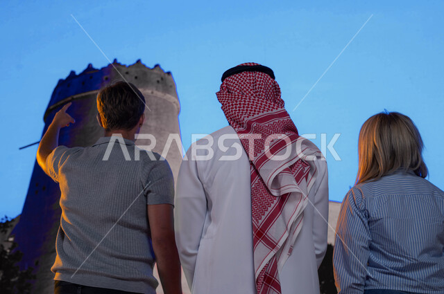 An Arab tourist guide, the distinctive wide walls in the old architectural building, the Museum of the Unification of Saudi Arabia, the historic Masmak Palace in the city of Riyadh, ancient historical tourist attractions, a close-up of a Saudi Arab youth 