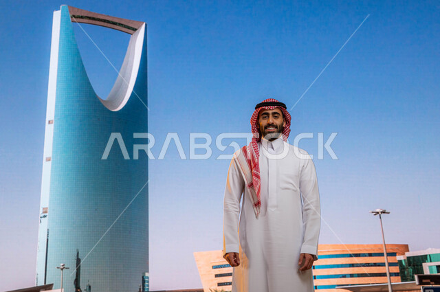 برج المملكة في مدينة الرياض في السعودية ،النمو العمراني والتطور, الفن الهندسي المعماري للابراج وناطحات السحاب، رجل عربي خليجي سعودي مبتسم يرتدي الثوب والشماغ وينظر الى الكاميرا بإيماءات السعادة، أماكن سياحية مشهورة