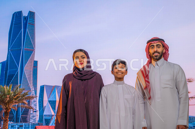 المنشأت المعمارية والأبراج المالية الاقتصادية، أماكن سياحية مشهورة, النمو والتطورالعمراني في الأحياء الجديده في الرياض, عائلة عربية خليجية تقف أمام مركز الملك عبدالله المالي ( كافد ) في السعودية و تنظر الى الكاميرا, الفن الهندسي للابراج وناطحات السحاب