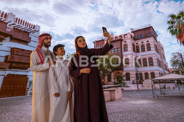 الرواشين الخشبيه في البناء المعماري العربي القديم ،التقاط الصور التذكارية عبر الهاتف المحمول، أنشطة عائلية ترفيهيه، زيارة المعالم السياحيه المشهوره في حي البلد، عائلة عربية خليجية سعودية مبتسمة تتجول بين الأحياء الشعبيه والمباني الأثرية في جده التاريخيه
