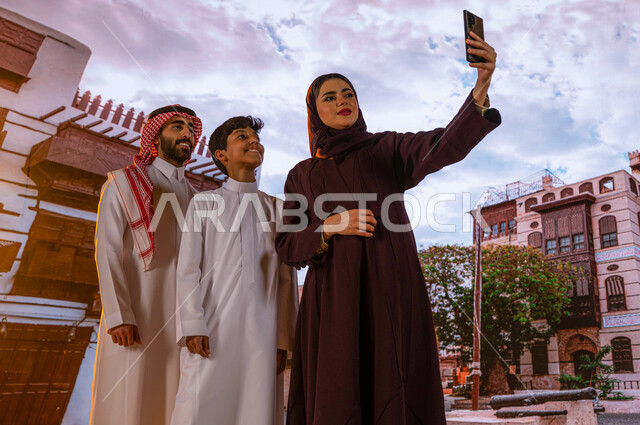 التقاط الصور التذكارية عبر الهاتف المحمول، أنشطة عائلية ترفيهيه، زيارة المعالم السياحيه المشهوره في حي البلد، عائلة عربية خليجية سعودية مبتسمة تتجول بين الأحياء الشعبيه والمباني الأثرية في جده التاريخيه, الرواشين الخشبيه في البناء المعماري العربي القديم