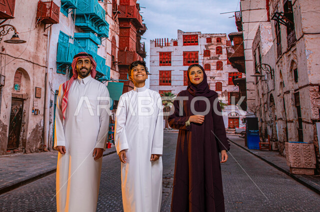 زيارة الأماكن والمعالم السياحيه المشهوره في حي البلد، انشطة ترفيهيه عائلية، عائلة عربية خليجية سعودية مبتسمة تنظر إلى شيء ما و تتجول بين الأحياء الشعبيه و المباني الأثرية في جده التاريخيه, الرواشين الخشبيه في البناء المعماري العربي القديم