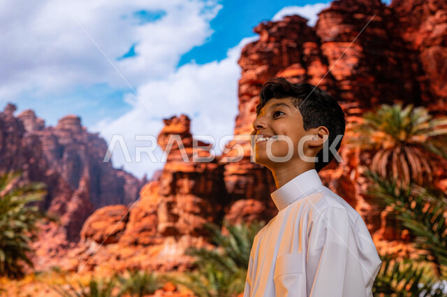 موقع أثري في اليونسكو، ايماءات تدل على الفرح والسعادة، صورة مقربة لولد عربي خليجي سعودي يرتدي الثوب التقليدي يقوم بزيارة أبرز المعالم التاريخية الأخاذة, زراعة النباتات و أشجار النخيل في الأماكن السياحيه المشهوره في محافظة العلا في السعوديه
