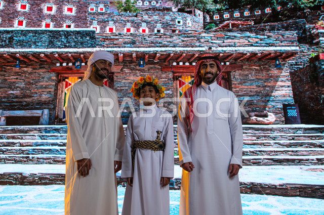 Antiquities and old historical houses in Abha, standing in front of the traditional village of Rijal Almaa, the arrival of tourists from all over the world, a Saudi man with an Emirati tourist and an Asiri boy wearing southern folk costume on a tourist tr