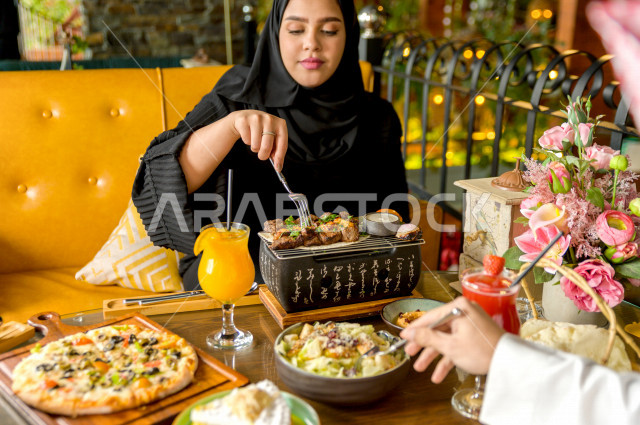 A close-up photo of a Saudi Arabian Gulf woman eating with her husband in the restaurant, spending a wonderful atmosphere in the restaurant, many types of food and dishes on the table, unique and distinctive sessions, restaurants and cafes in Saudi Arabia