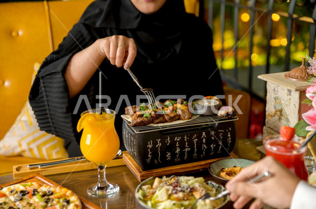 صورة مقربة لمائدة طعام خاصة بزوجين عربيين خليجيين سعوديين ، يجلسان على مائدة الطعام و يتناولان الطعام في المطعم ، قضاء اجواء رائعة  في المطعم ، تشكيلة متنوعة من أصناف الطعام و الماكولات الشهية على الطاولة ، جلسات فريدة و مميزة ، مطاعم و كافيهات في السعودي