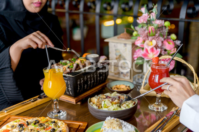 صورة مقربة لمائدة طعام خاصة بزوجين عربيين خليجيين سعوديين ، يجلسان على مائدة الطعام و يتناولان الطعام في المطعم ، قضاء اجواء رائعة  في المطعم ، تشكيلة متنوعة من أصناف الطعام و الماكولات الشهية على الطاولة ، جلسات فريدة و مميزة ، مطاعم و كافيهات في السعودي