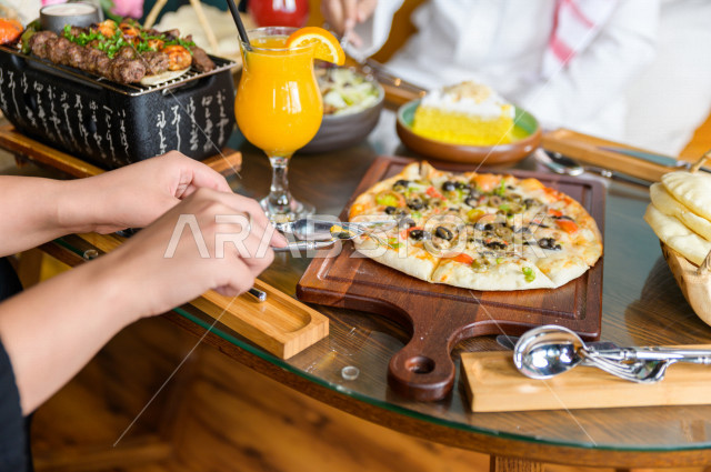 صورة مقربة لمائدة طعام خاصة بزوجين عربيين خليجيين سعوديين ، يجلسان على مائدة الطعام و يتناولان الطعام في المطعم ، قضاء اجواء رائعة  في المطعم ، تشكيلة متنوعة من أصناف الطعام و الماكولات الشهية على الطاولة ، جلسات فريدة و مميزة ، مطاعم و كافيهات في السعودي