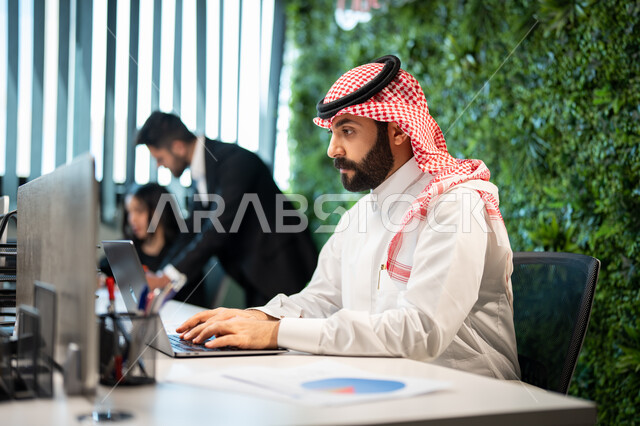 مهن ووظائف سعودية، تدوين و تسجيل النتائج و الملاحظات, موظف عربي سعودي خليجي يرتدي الشماغ و الثوب السعودي التقليدي يقوم بإنجاز مهام العمل اليومية، دمج الأعمال مع التقنية و التكنولوجيا, تحقيق أهداف الشركة, الوحدة والعمل الجماعي.