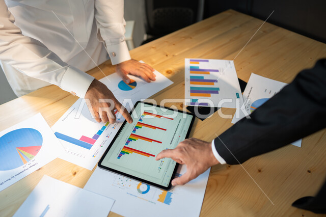 بيانات إنجاز وتحقيق اهداف الشركة، صورة علوية عامودية مقربة لاجتماع رجال أعمال عربيين سعوديين خليجيين داخل مقر الشركة، مفهوم الإدارة المتعاونة، جمع بيانات البورصه وسوق الأسهم, دراسة و تحليل الاحصائيات و الرسوم البيانية, دمج التكنولوجيا مع العمل.