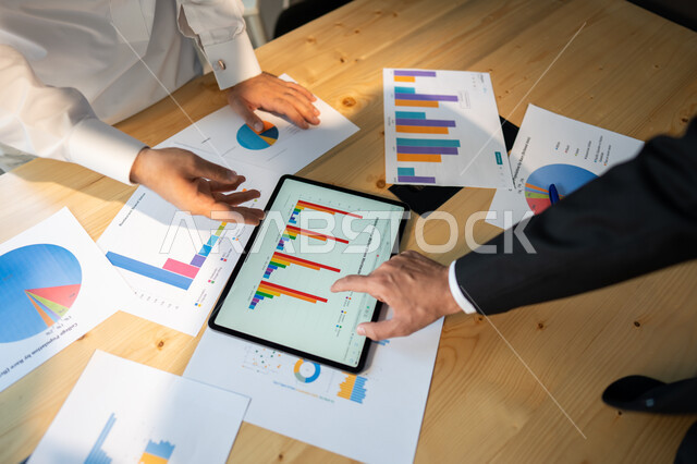 بيانات إنجاز وتحقيق اهداف الشركة، صورة علوية عامودية مقربة لاجتماع رجال أعمال عربيين سعوديين خليجيين داخل مقر الشركة، مفهوم الإدارة المتعاونة، جمع بيانات البورصه وسوق الأسهم, دراسة و تحليل الاحصائيات و الرسوم البيانية, دمج التكنولوجيا مع العمل.