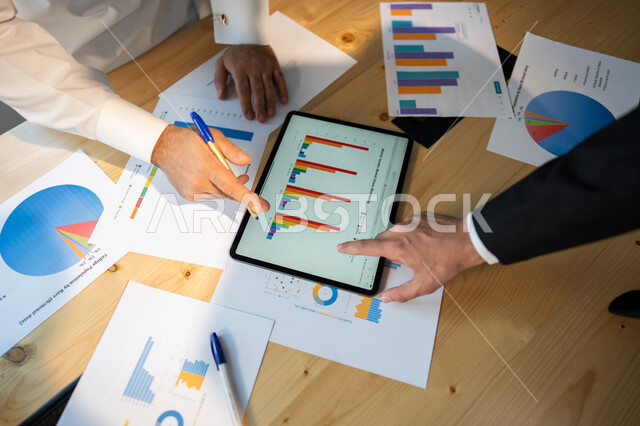 تحقيق الاهداف المالية للشركة، صورة علوية عامودية مقربة لاجتماع رجال فريق عمل عربي خليجي سعودي، مفهوم الإدارة المتعاونة، جمع بيانات البورصه وسوق الأسهم, دراسة و تحليل الاحصائيات و الرسوم البيانية, دمج التكنولوجيا مع العمل.