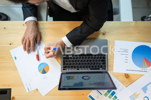 مراقبة نزول وصعود البورصة والأسهم المالية، تطوير استراتيجية العمل وخطة النمو، صورة علوية عامودية مقربة لموظف ينجز مهام العمل باستخدام الحاسوب، قسم التحليلات والإحصائيات البيانية، بيانات خسائر وارباح الشركة.