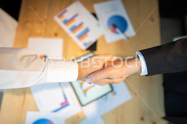 التعاون بين الشركات العربية الخليجية السعودية، متابعة نزول وصعود أسهم البورصة، الاستثمار المالي والاقتصادي، رجلا اعمال عربيان خليجيان سعوديان يتصافحان، الإتفاق والشراكة على صفقة عمل جديدة, بيانات خسائر وارباح الشركة.