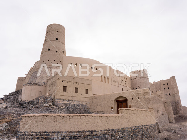 موقع استراتيجي هام, منظر السماء الملبدة بالغيوم, قلعة بهلاء عبري مبنية من الطين في سلطنة عمان , معلم عسكري تاريخي اثري ،التصميم والفن الهندسي المعماري بالطراز الهندسي القديم،  معالم سياحيه تراثيه مشهورة .
