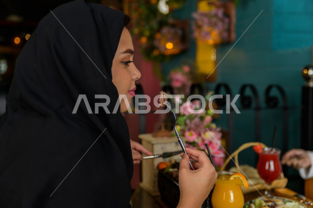 صورة مقربة لسيدة عربية خليجية سعودية تتناول الطعام في المطعم ، قضاء اجواء رائعة  في المطعم ، العديد من أصناف الطعام و الماكولات على الطاولة ، جلسات فريدة و مميزة ، مطاعم و كافيهات في السعودية