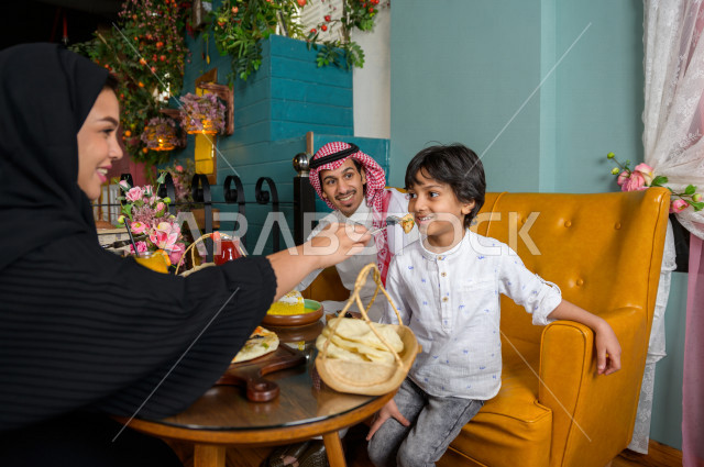 عائلة عربية خليجية سعودية تقضى وقتا ممتعا على مائدة الطعام في المطعم ، قضاء أوقات عائلية ترفيهية ، تشكيلة متنوعة من أصناف الطعام و المأكولات الشهية على الطاولة ، جلسات فريدة و مميزة ، مطاعم و كافيهات في السعودية